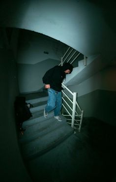 a man is walking up some stairs in the dark with his hand on his hip