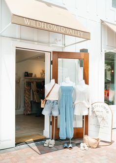 a store front with clothing on display in the window and an open sign that says wildflower valley