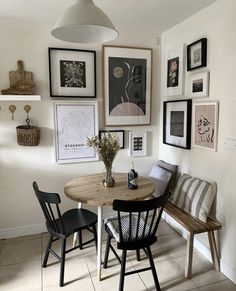 a dining room table with chairs and pictures on the wall above it in front of a bench