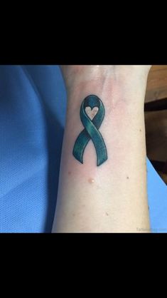 a green ribbon with a heart tattoo on the wrist