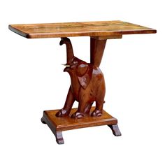 a wooden table with an elephant sculpture on it's legs and one leg raised up