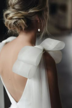 the back of a woman's neck wearing a white dress with large bows on it