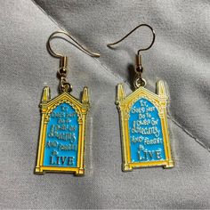 the earrings are blue and gold with words on them that read, it's not too