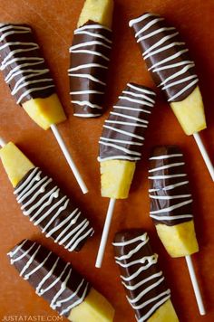 chocolate covered pineapples with white and yellow icing are on a wooden table