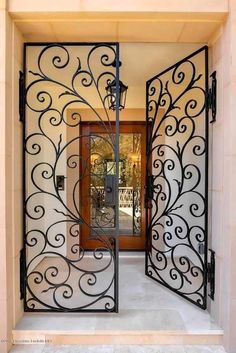 an ornate iron gate in front of a door that has a glass paneled entrance