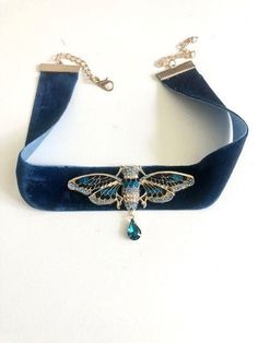 Blue and gold Cicada art deco necklace with crystal drop on blue velvet ribbon: the necklace is made of a blue velvet ribbon 2.5 cm high, x 42 cm (with the chains, i.e. 30 cm of velvet) on which is attached a pretty cicada in gold metal enameled in blue and dotted with blue rhinestones. A small drop of blue crystal hangs under the cicada. The ribbon attaches with a carabiner. Available as a pendant mounted on a stainless steel chain, on sale separately in the store: https://www.etsy.com/fr/listing/979591227/collier-art-deco-cigale-bleu-et-or-avec?click_key= 67205b7f75a392aeb0c40d21a435d5c68e8ddea2%3A979591227&click_sum=a0584fc9&ga_search_query=cigale&ref=shop_items_search_1&sca=1 All my jewelry is packaged with care, and delivered in tracked parcel or international tracking. I communicate Necklace With Ribbon, Ribbon Necklace With Pendant, Blue Jewelry Aesthetic, Cicada Art, Cicada Necklace, Blue Velvet Ribbon, Velvet Accessories, Velvet Necklace, Jewelry Aesthetic