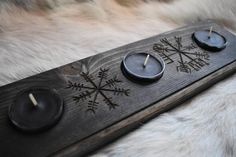 two candles are sitting on top of a wooden board with snowflakes and arrows