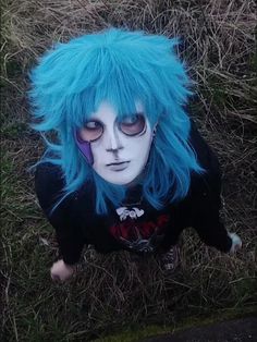 a person with blue hair and makeup laying on the ground