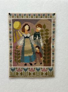 a cross stitch picture with an image of a woman and two children in the woods