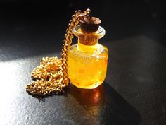 a small glass bottle sitting on top of a table next to a gold chain necklace