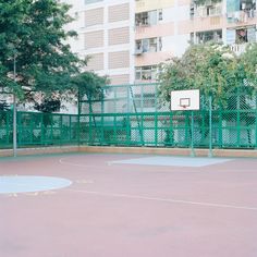 an outdoor basketball court with trees and buildings in the background