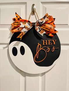 a door hanger with a black and white pumpkin hanging from it's side