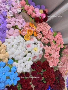 many different colored flowers on display for sale