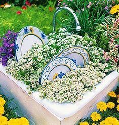 an arrangement of dishes and flowers in a garden