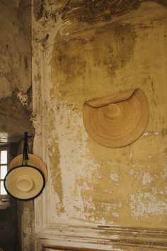 two hats hanging on the wall in an old building with peeling paint and chipped walls