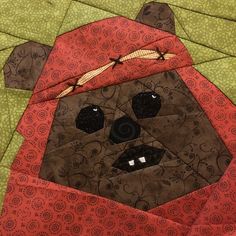 a brown bear wearing a red hat and scarf on top of a quilted surface