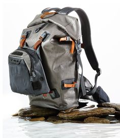 a backpack is sitting on some rocks in the water and it's zippered up