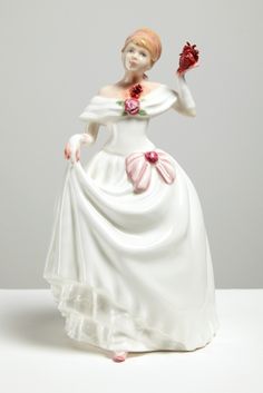 a ceramic figurine of a woman in a white dress holding a flower bouquet