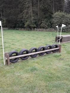 a row of tires sitting on top of a grass covered field next to a wooden bench