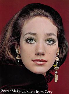 an old photo of a woman with makeup on her face and wearing large gold earrings