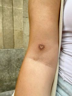 a woman's arm with a small sun tattoo on the left side of her arm