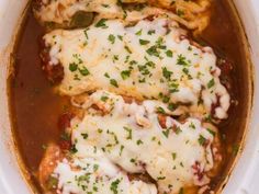 chicken enchilada casserole in a white crock pot with cheese on top