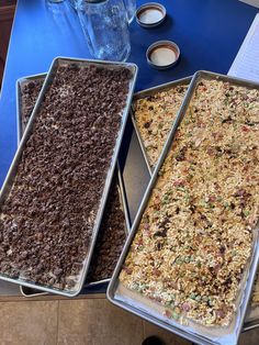 three pans filled with food sitting on top of a blue table next to each other