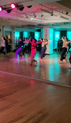 a group of people dancing in a large room with mirrors on the wall and floor