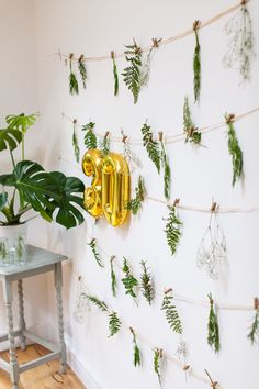 a wall decorated with plants and gold balloons that spell out the word'love '