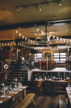 the interior of a restaurant with tables, chairs and flags hanging from the ceiling above