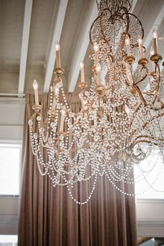 a chandelier hanging from the ceiling in a room with curtains and drapes