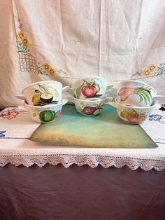 a table topped with bowls and plates covered in fruit painted on it's sides