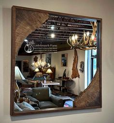 a mirror reflecting the inside of a living room with furniture and lamps on it's sides