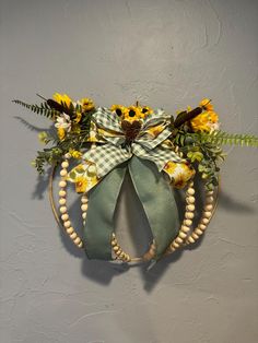 a wreath with sunflowers and greenery hangs on the wall in front of a gray wall