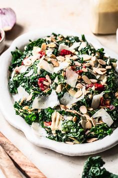 a white bowl filled with greens and nuts