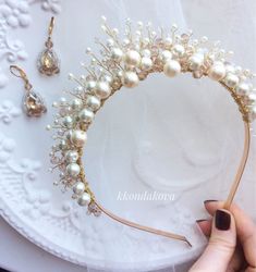 a woman is holding a tiara with pearls on it