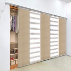 an empty room with sliding doors and clothes on hangers in the closet, next to a white wall