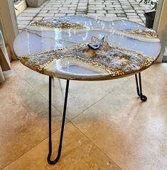 a table that is sitting on some sort of metal legs with gold and white designs