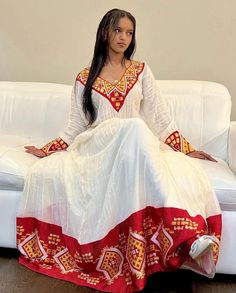 Ethiopian and Eritrean traditional white dress with intricate red, yellow, and gold embroidery. The dress has a distinctive cultural style, possibly Ethiopian or Eritrean, based on the patterns and colors. elegant dress looks like beautiful dress any ceremony Habesha Traditional Dresses, Zuria Habesha Dress, Ethiopia Clothing, Eritrean Clothing, Eritrean Dress, Mother Africa, Ethiopian Clothing, Habesha Dress, Ethiopian Traditional Dress