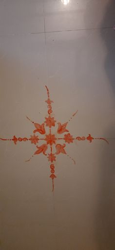 an orange flower is drawn on the floor in front of a white wall and ceiling