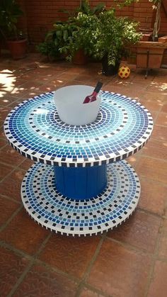 a blue and white table sitting on top of a red brick floor next to potted plants