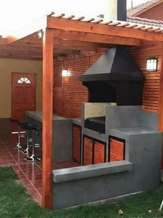 an outdoor kitchen is built into the side of a house with wood slats on it