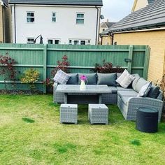 a grey couch sitting on top of a green grass covered field next to a wooden fence