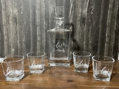 four shot glasses and a decante bottle on a wooden table