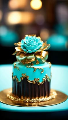 a blue and gold decorated cake sitting on top of a golden plate with a flower