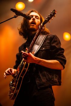 a man with long hair playing an electric guitar