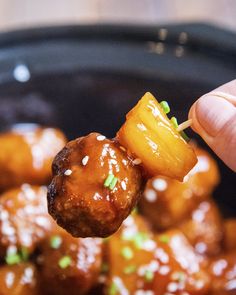 a hand holding up a piece of meat with pineapple on the skewer