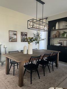 a dining room table with black chairs and white vases on it's centerpiece