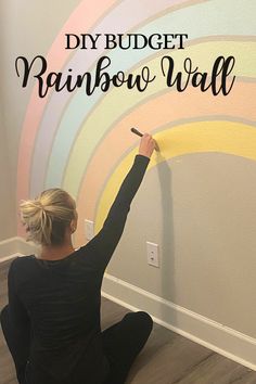 a woman sitting on the floor painting a rainbow wall with text overlay that reads diy budget rainbow wall