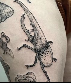 a close up of a person's thigh with tattoos on it and an insect